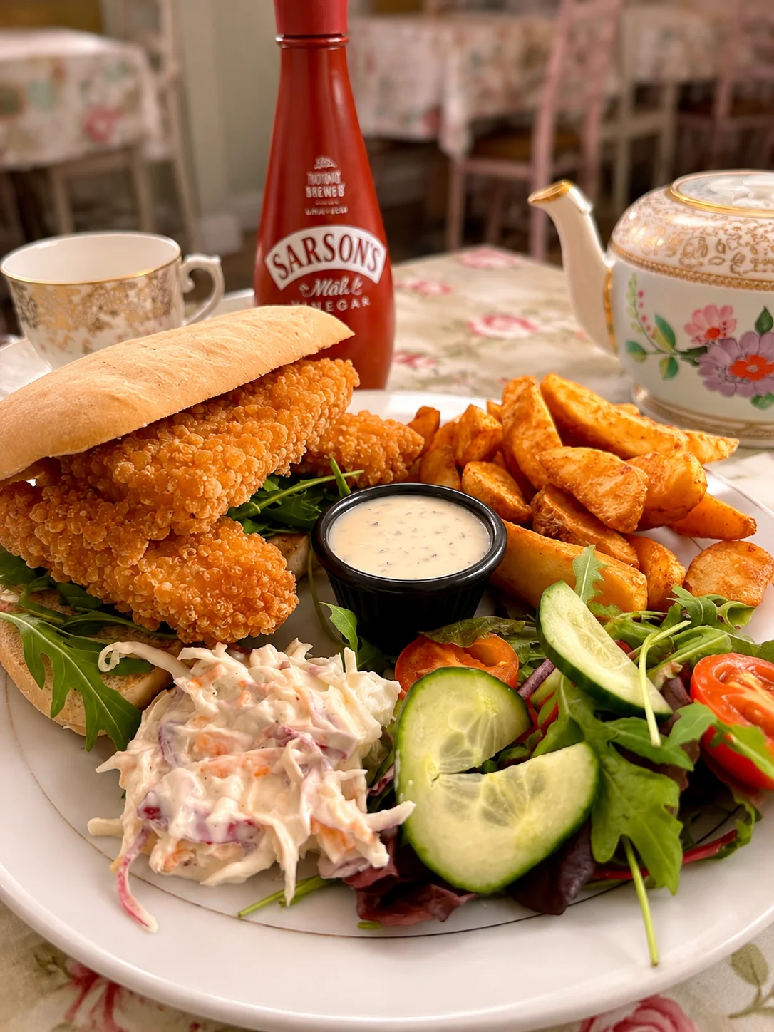A crispy chicken sandwich served with potato wedges, salad and coleslaw